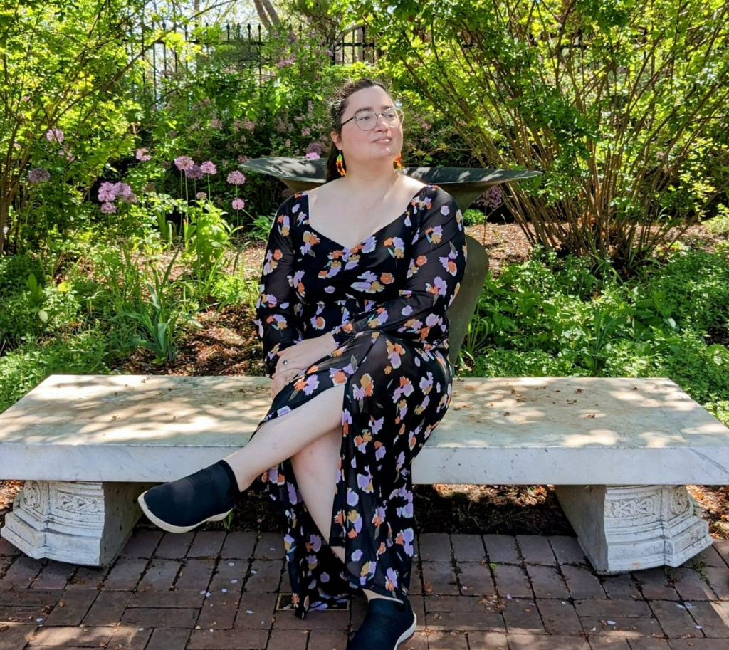 Nour al-Zaghloul sitting on a stone bench with plants in the background