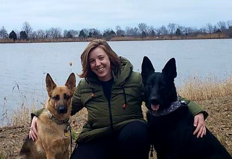 Kelsey with 2 dogs in front of a lake.