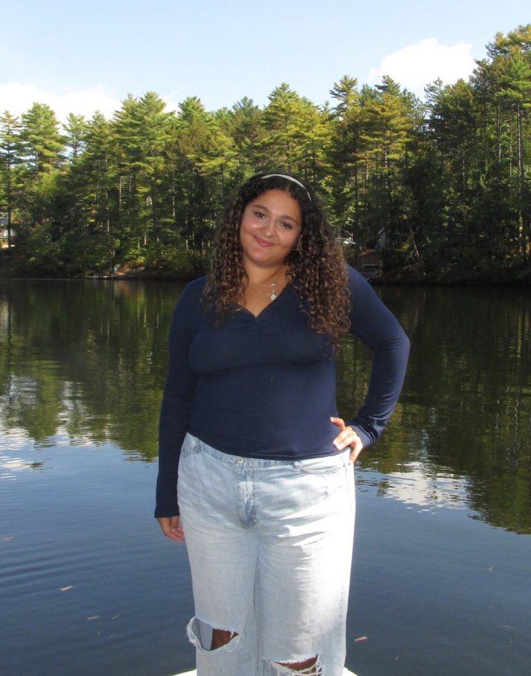 Kermina standing in front of a forest lake.